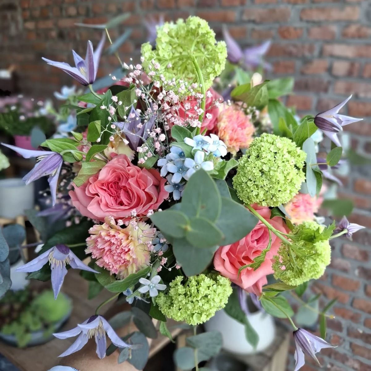 Bouquet de printemps : roses saumon, boules de neige, clématites et eucalyptus